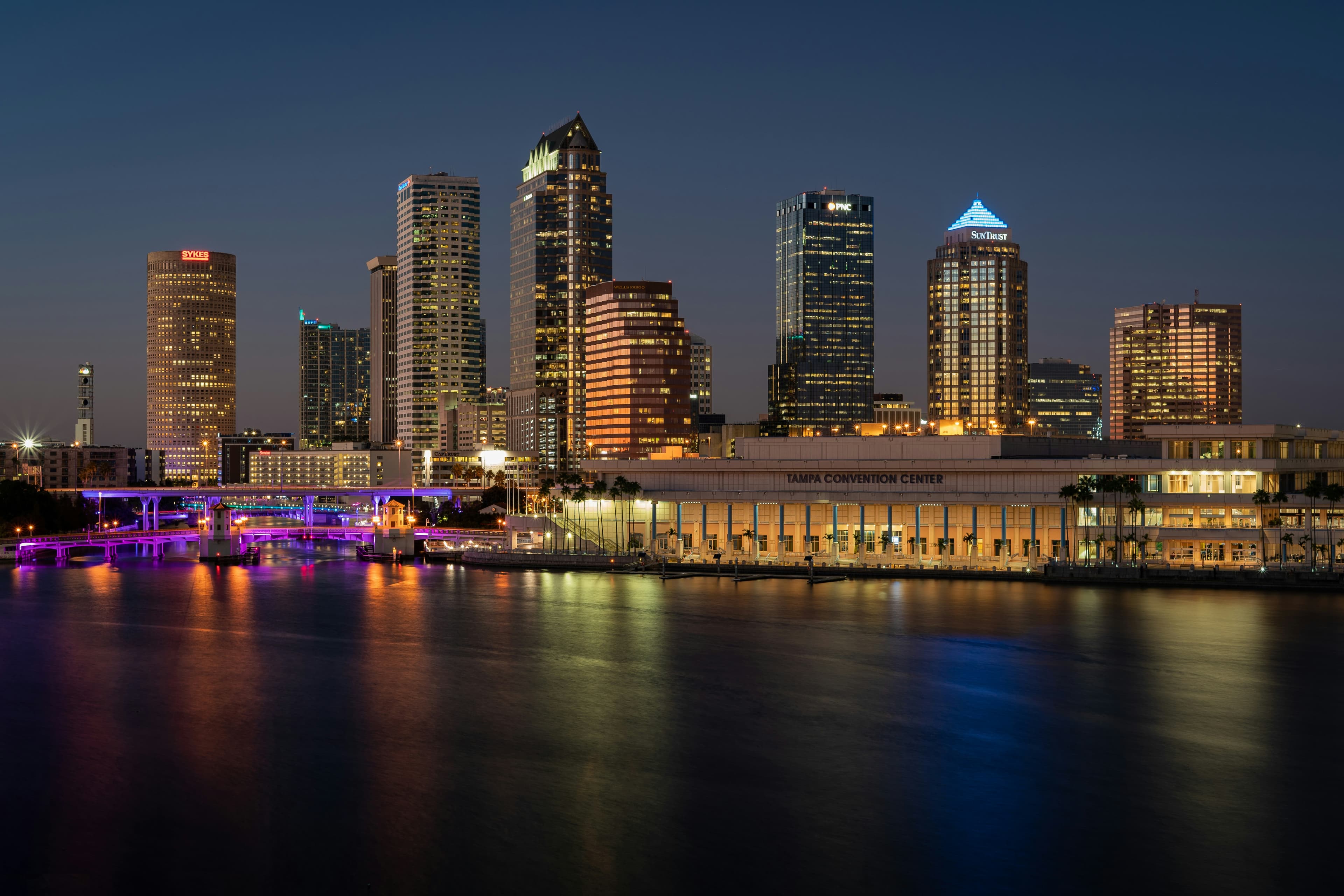 Illuminated Tampa skyline and convention center reflecting on the Hillsborough River at night.